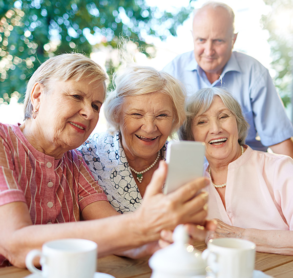 group of 4 seniors looking at photos on a smartphone